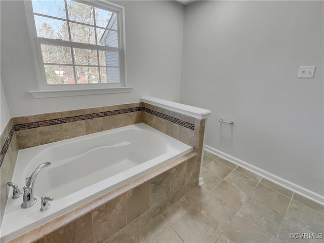 full bath featuring tiled tub and baseboards