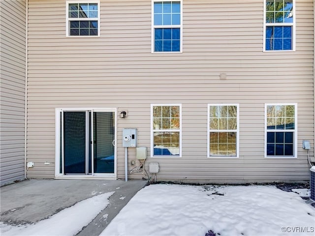 snow covered back of property featuring a patio area