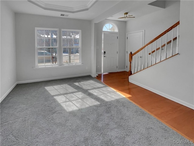 entryway with stairway, a raised ceiling, visible vents, and baseboards