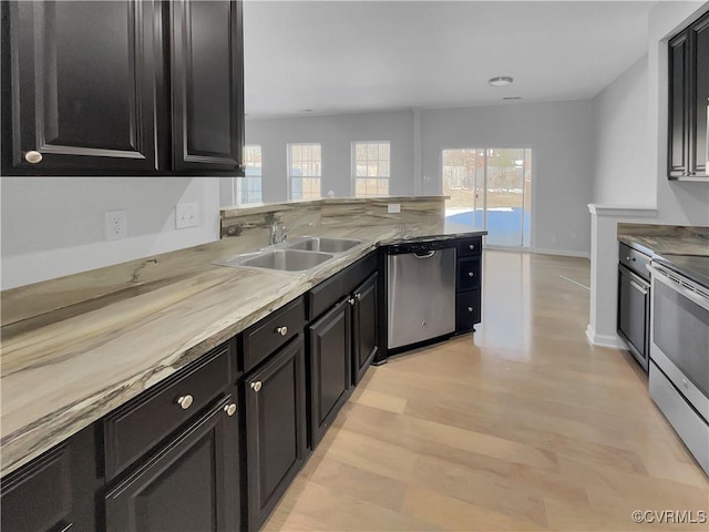 kitchen featuring dark cabinets, appliances with stainless steel finishes, light countertops, and a sink