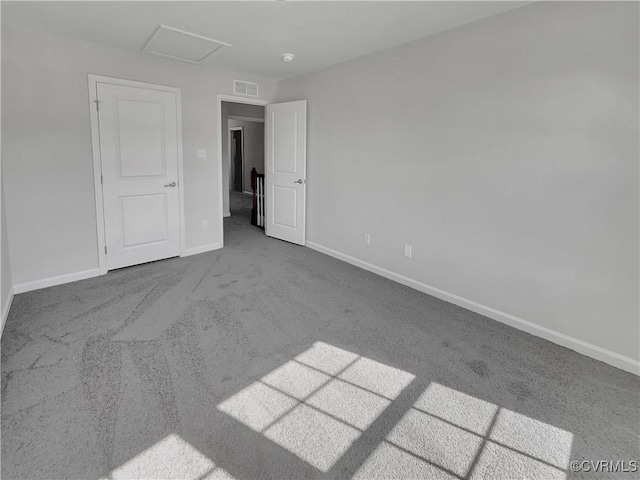 unfurnished bedroom with carpet, attic access, visible vents, and baseboards