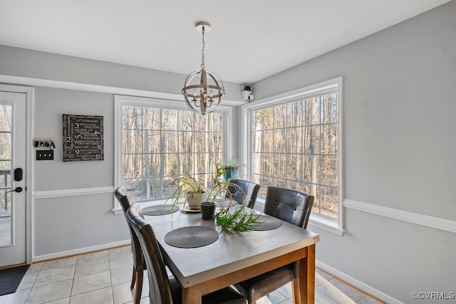 dining room with baseboards, light tile patterned flooring, a wealth of natural light, and a notable chandelier