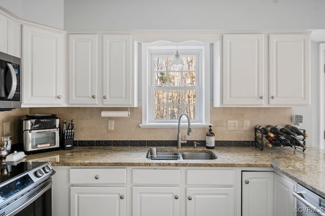 kitchen featuring appliances with stainless steel finishes, white cabinetry, and a sink