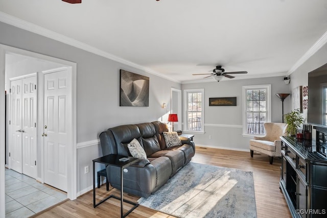 living room featuring light wood-type flooring, ceiling fan, ornamental molding, and baseboards