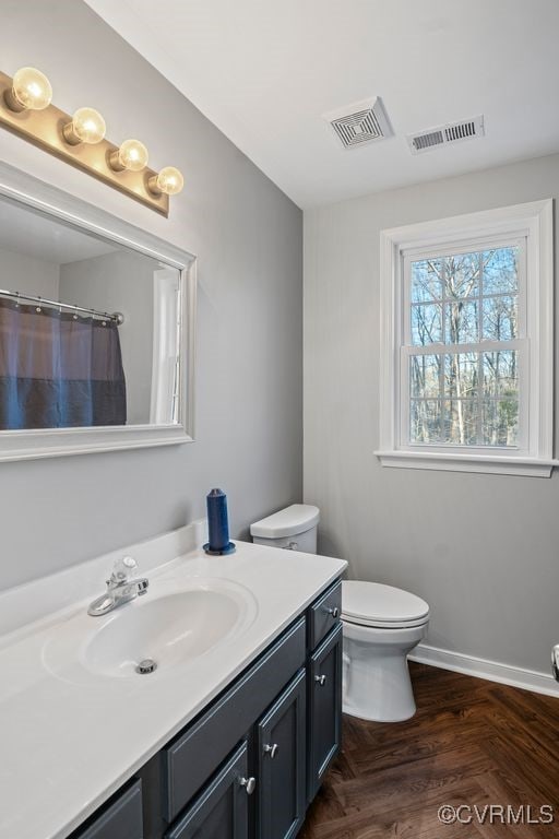 bathroom featuring toilet, vanity, visible vents, and baseboards