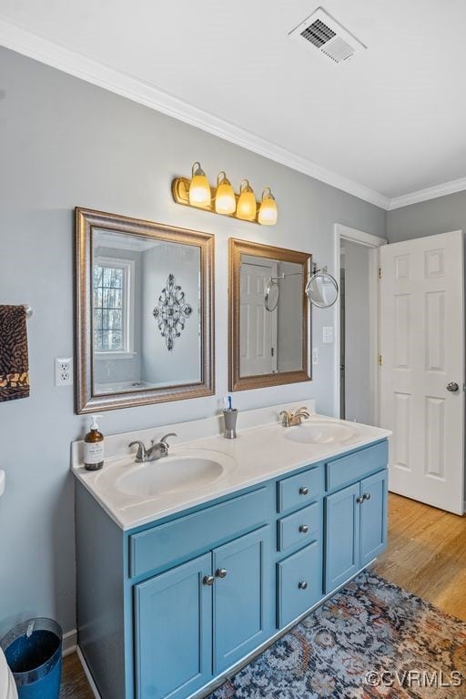 full bath with crown molding, visible vents, a sink, and wood finished floors