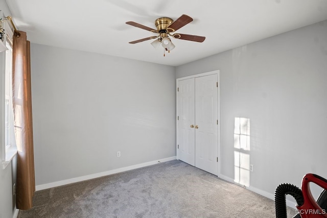 unfurnished bedroom with ceiling fan, a closet, baseboards, and carpet flooring