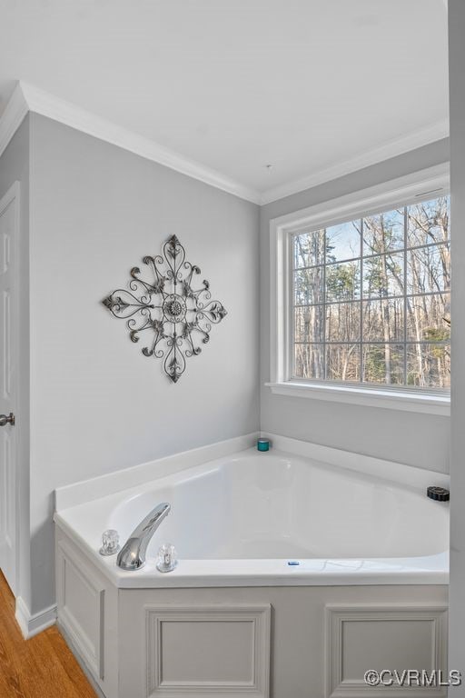 bathroom featuring ornamental molding, a garden tub, and wood finished floors