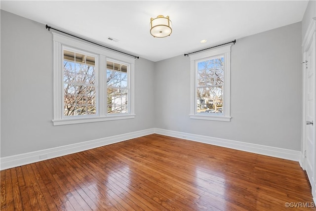 spare room with visible vents, hardwood / wood-style floors, and baseboards