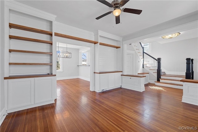 interior space featuring stairs, baseboards, dark wood-type flooring, and ceiling fan with notable chandelier