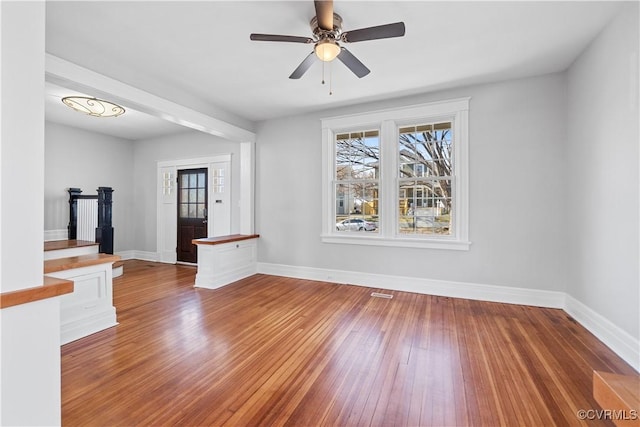 interior space featuring a ceiling fan, baseboards, and hardwood / wood-style floors