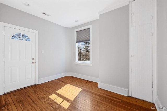 foyer entrance with baseboards, visible vents, and wood finished floors