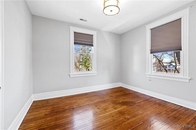 empty room with visible vents, baseboards, and hardwood / wood-style floors