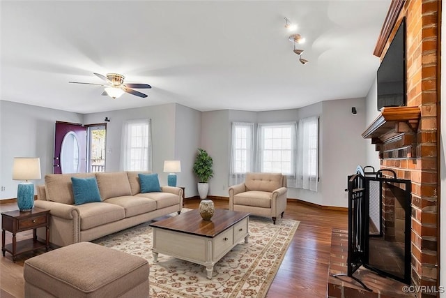 living room featuring a fireplace, wood finished floors, a ceiling fan, and baseboards