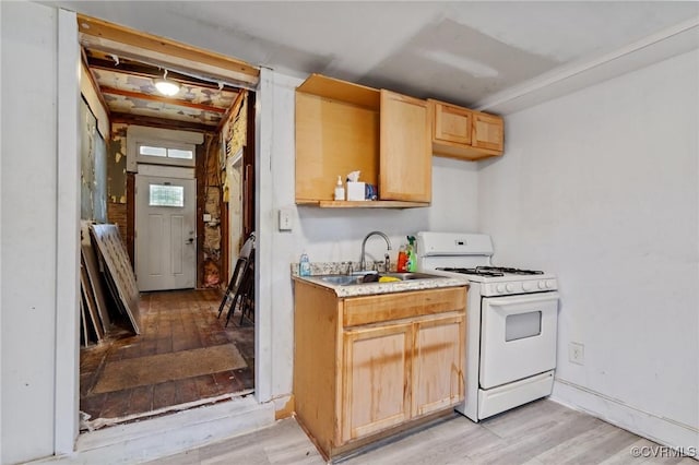 kitchen featuring light countertops, light brown cabinets, white range with gas cooktop, a sink, and light wood-type flooring