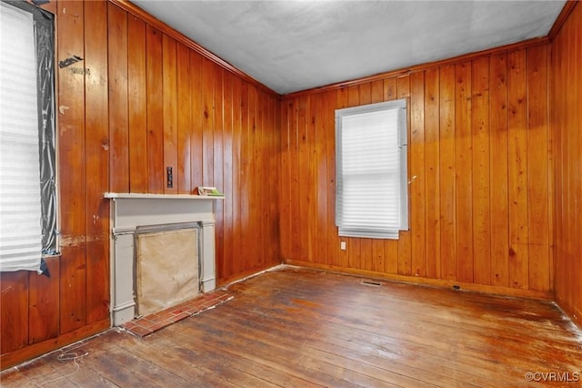 unfurnished living room featuring visible vents, a fireplace, hardwood / wood-style flooring, and wooden walls