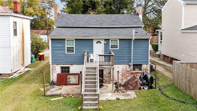 rear view of property featuring a chimney, fence, stairway, and a lawn