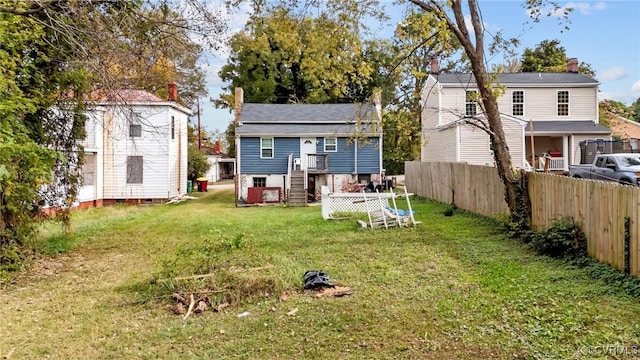 rear view of house featuring a yard, fence, and a chimney