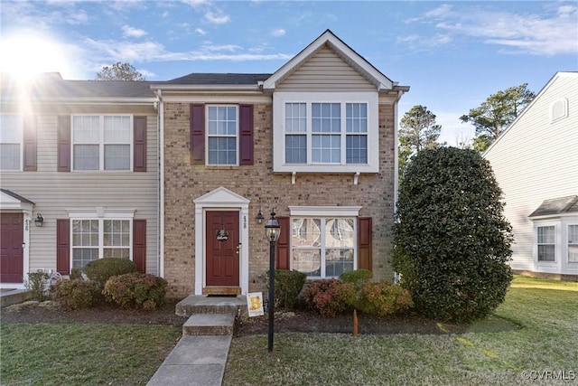 townhome / multi-family property featuring a front lawn and brick siding