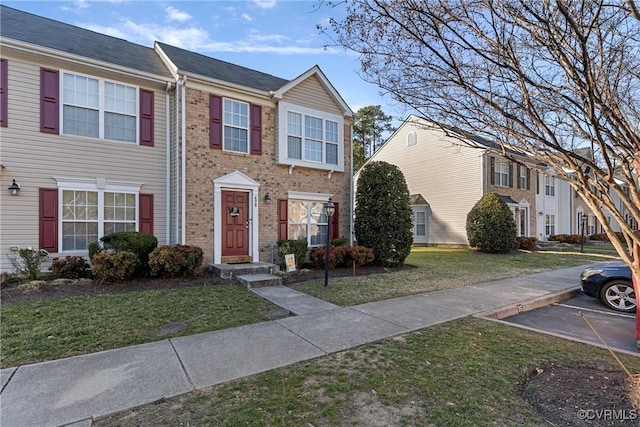 view of property featuring brick siding, a front yard, and uncovered parking