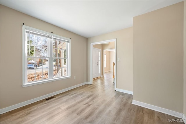 unfurnished room featuring light wood-style floors, visible vents, and baseboards