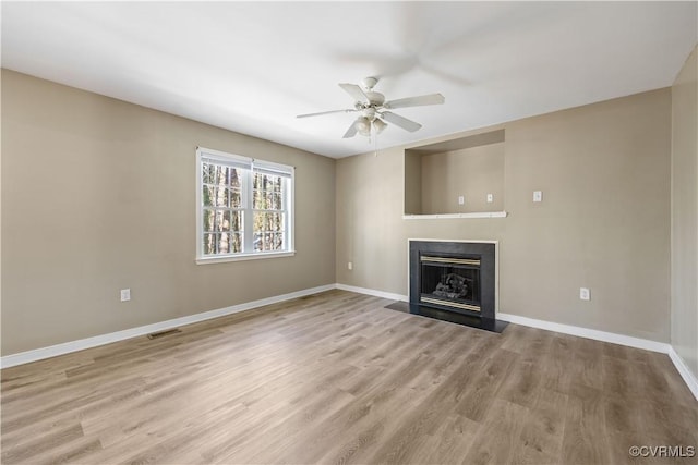 unfurnished living room with ceiling fan, light wood-type flooring, a fireplace with flush hearth, and baseboards