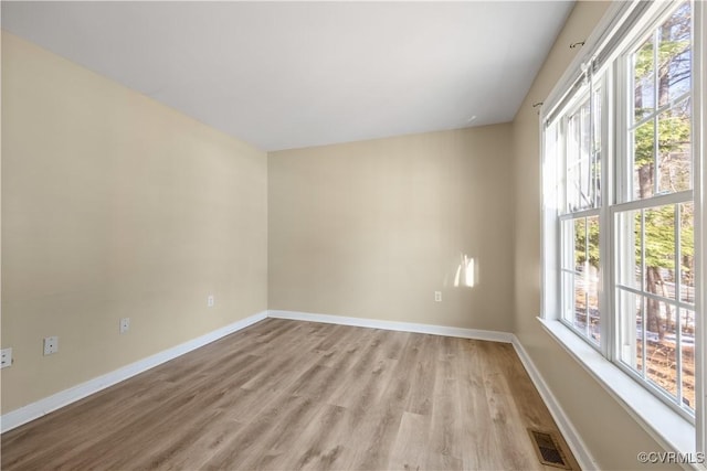 unfurnished room featuring visible vents, light wood-style flooring, and baseboards