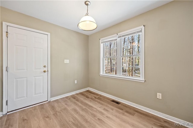 spare room with light wood-type flooring, visible vents, and baseboards