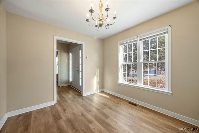 unfurnished dining area with a chandelier, light wood-type flooring, visible vents, and baseboards