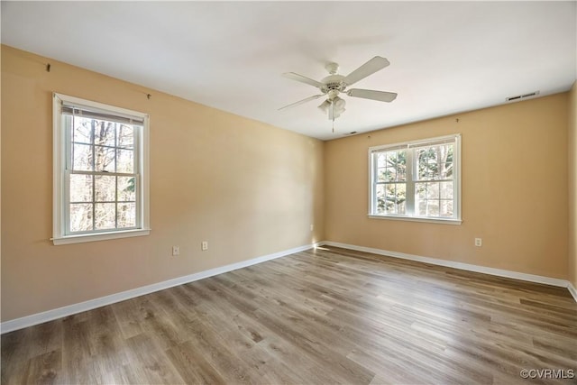 unfurnished room with plenty of natural light, visible vents, and wood finished floors