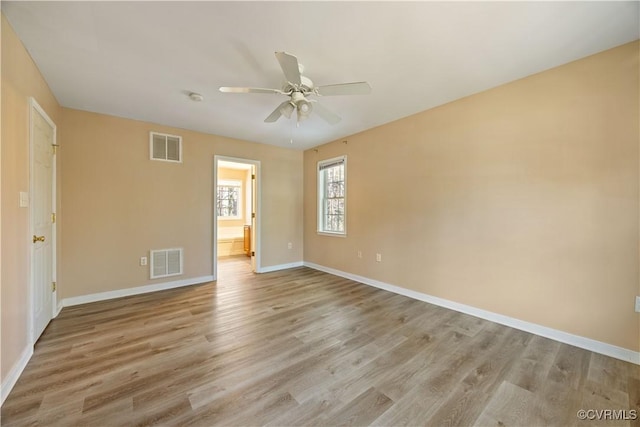 empty room featuring a ceiling fan, light wood-type flooring, visible vents, and baseboards