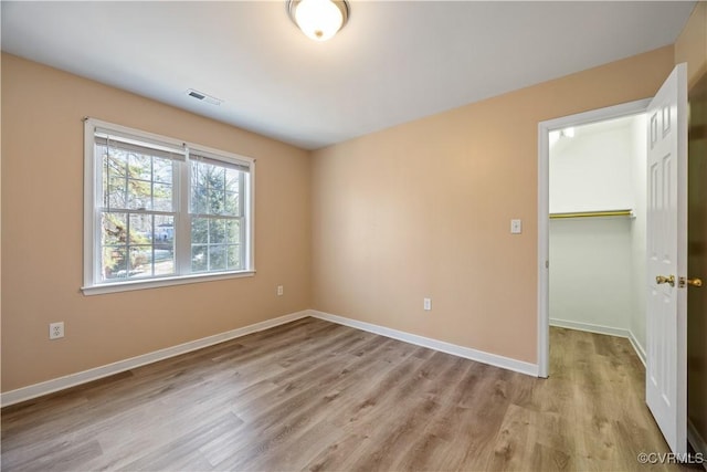 unfurnished room featuring visible vents, light wood-style flooring, and baseboards