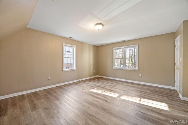 interior space with baseboards, vaulted ceiling, wood finished floors, and a healthy amount of sunlight