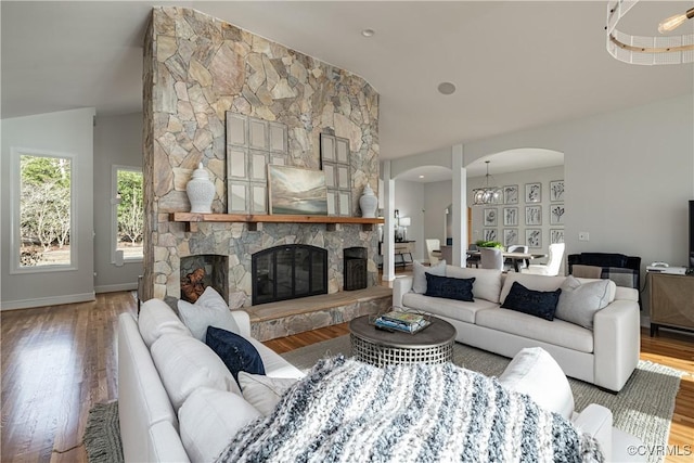 living area with arched walkways, vaulted ceiling, and wood finished floors