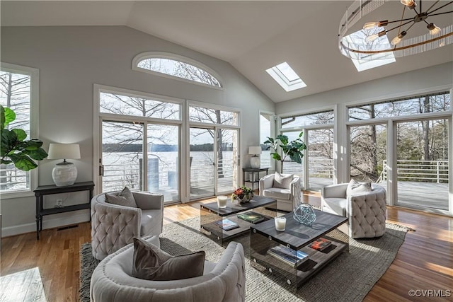 living area featuring a chandelier, visible vents, a skylight, and wood finished floors