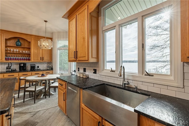 kitchen with tasteful backsplash, dishwasher, a sink, and dark stone countertops