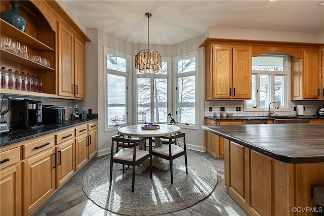 kitchen with a notable chandelier, a sink, decorative backsplash, and dark countertops