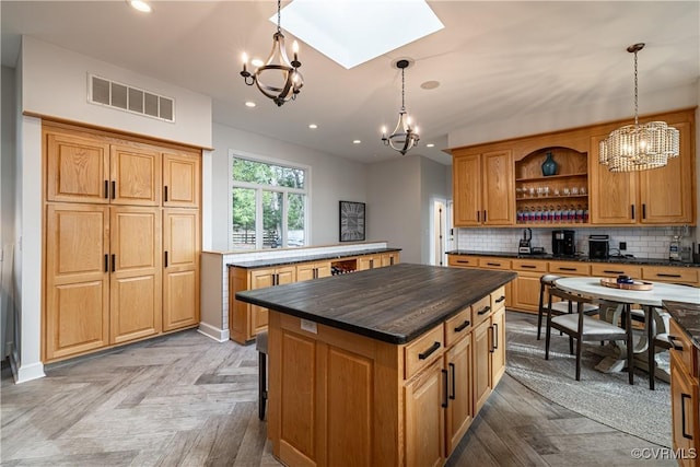 kitchen featuring visible vents, open shelves, a chandelier, a skylight, and a kitchen island