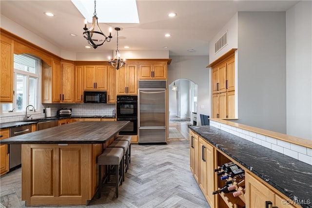 kitchen featuring a notable chandelier, backsplash, visible vents, arched walkways, and black appliances