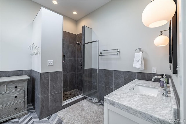 bathroom with vanity, recessed lighting, tile patterned flooring, tiled shower, and tile walls