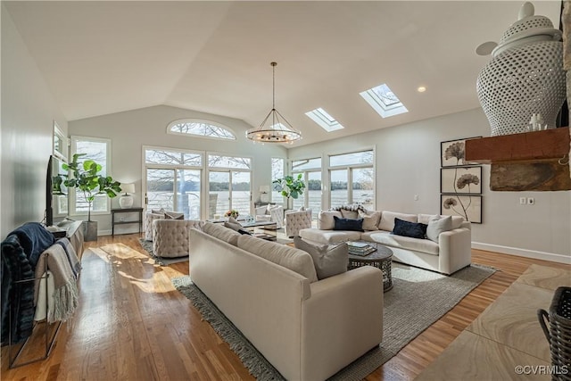 living room featuring a wealth of natural light, lofted ceiling with skylight, wood finished floors, and baseboards