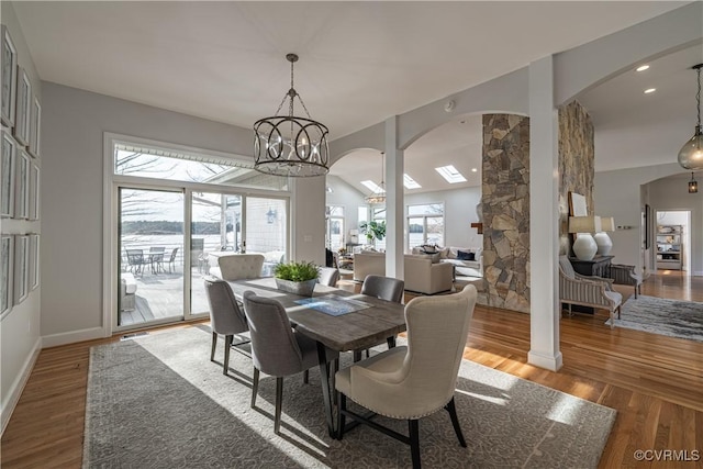 dining space with baseboards, arched walkways, a chandelier, and wood finished floors