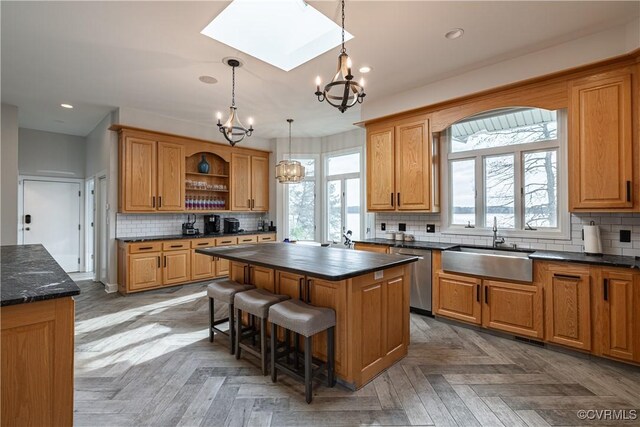 kitchen featuring stainless steel dishwasher, a chandelier, a center island, a sink, and plenty of natural light