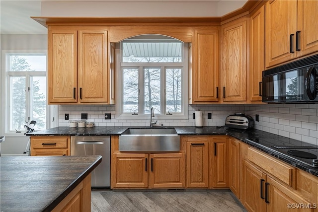 kitchen featuring plenty of natural light, a sink, black appliances, and decorative backsplash