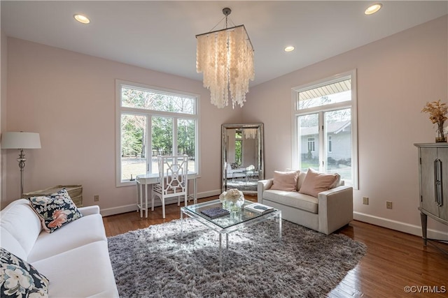 living area featuring wood finished floors, an inviting chandelier, baseboards, and plenty of natural light