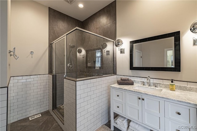 bathroom with visible vents, tile walls, a shower stall, recessed lighting, and vanity