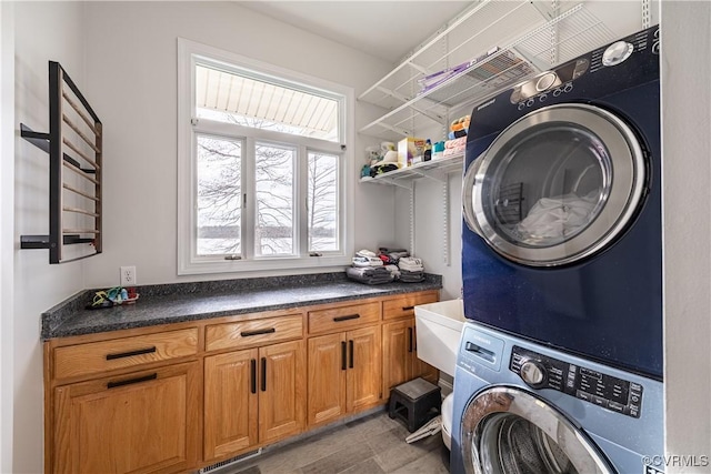 laundry area with cabinet space, visible vents, and stacked washer / drying machine