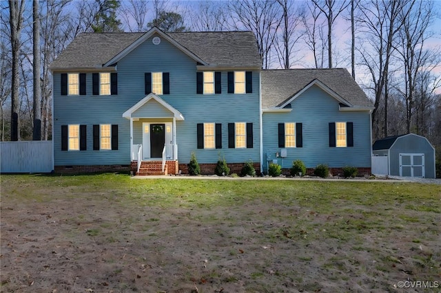 colonial home with an outbuilding, fence, crawl space, a shed, and a front yard