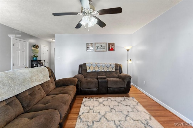 living area featuring light wood-style floors, ceiling fan, and baseboards