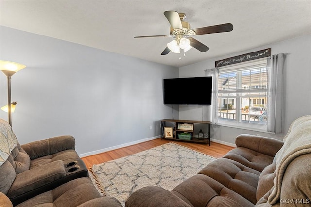 living area featuring ceiling fan, light wood-type flooring, and baseboards